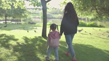 Anne ve kızı yeşil bir parkta huzurlu bir yürüyüş yapıyorlar.