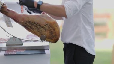 Şef, özel bir tutucuya yerleştirilmiş bir bacağından ince dilim İber jambonu ustalıkla kesiyor.