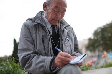 Dışarıda kulaklıkla müzik dinlerken notlar alan kıdemli bir gazeteci.