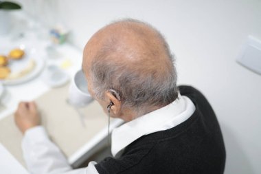 İşitme cihazı takan son sınıf öğrencisi kahvaltıda eğleniyor.