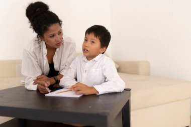 Öğretmen, genç öğrenciye bir sınıf ortamında ödev yazma konusunda yardım ediyor.