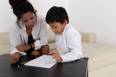 Genç öğrenci evde yardımcı öğretmenle alfabe mektupları yazıyor.