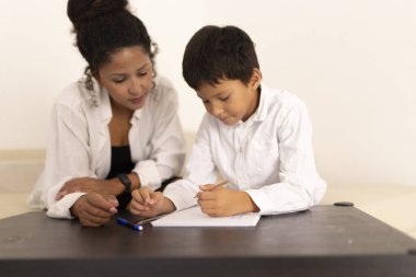 Anne, oğluna ev ödevlerinde yardım ediyor, eğitime ve evde eğitime odaklanıyor.