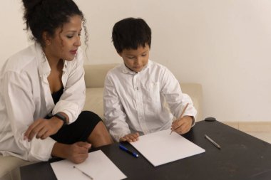 Anne ve oğlu evde kalemleri kağıt üzerine çizerek vakit geçiriyorlar.