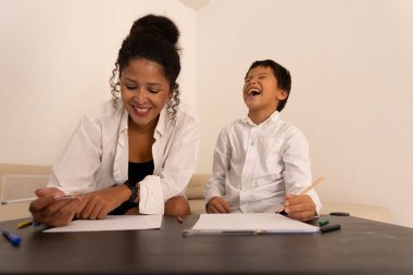 Mutlu anne ve oğul evde birlikte çiziyor, eğleniyor ve gülüyorlar.