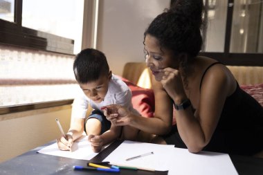 Anne ve oğul evde birlikte resim çiziyor, kaliteli zaman geçiriyor ve yaratıcılığı destekliyorlar.