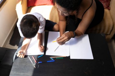 Anne ve oğul sanat üzerine bağ kuruyor, evde birlikte çiziyorlar, yaratıcılığı ve aile bağını teşvik ediyorlar.