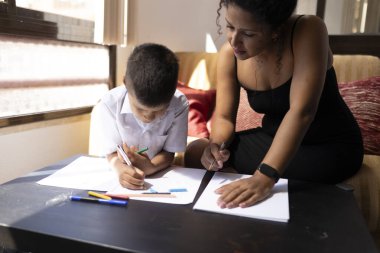Evde özel ders sırasında renkli kalemler kullanarak Latin öğrencilere resim çizdirmeye odaklanmış İspanyol öğretmen.