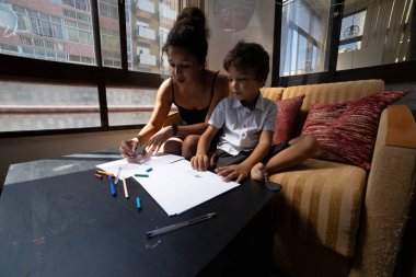 Anne ve oğlu birlikte güzel vakit geçiriyorlar. Oturma odalarında pastel boyalarla resim çiziyorlar.