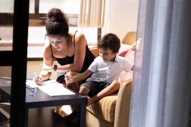 Anne oğluna evde eğitim konusunda yardım ediyor, rehberlik ve destek sağlıyor.