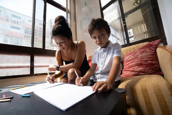 Anne ve oğlu parlak bir oturma odasındaki masada resim çiziyorlar.