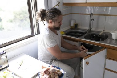 Mutfakta yemek pişirirken tavuk kemiklerini çöp poşetine atan korkunç adam.