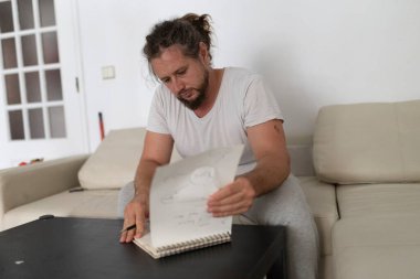 Yaratıcı adam yeni tasarım üzerinde çalışıyor, defterine çizimler çiziyor.