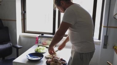 Ev aşçısı tavuk yemeği hazırlıyor, sebze doğruyor ve et kesiyor.