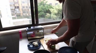 Profesyonel şef, ahşap kesme tahtasındaki pırasaları ustalıkla dilimliyor. Lezzetli bir mutfak yaratımı için malzemeler hazırlıyor.