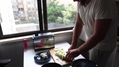 Profesyonel aşçı evde pırasa hazırlıyor, onları dilimliyor ve tabağa koyuyor.