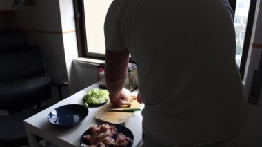 Adam mutfakta tavuk eti kesiyor.