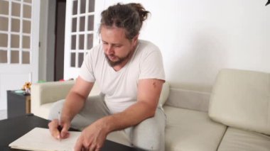 Odaklanmış sanatçı oturma odasındaki çizim defterine çizim yapıyor.