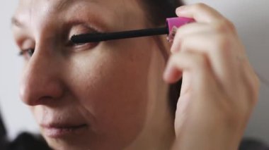 Yüzüne maskara ve makyaj yapan beyaz bir kadın.