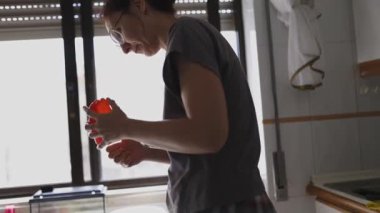 Parlak bir mutfakta kırmızı biber soyan kızıl saçlı kadın.