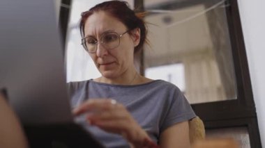 Ev ofisinden uzaktan çalışan, dizüstü bilgisayar klavyesinde yazan odaklanmış bir kadın.