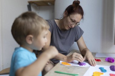 Anne ve oğul birlikte kaliteli zaman geçiriyorlar, evlerinde killi modeller yaparak renkli sanat eserleri yaratıyorlar.