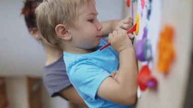 Hevesli bir anaokulu öğrencisi destekleyici bir öğretmenin rehberliğinde renkli bir modelleme kiliyle yaratıcılığı keşfediyor.