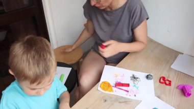 Bir anne ve oğlunu içeren yaratıcı aile aktivitesi kağıt üzerine renkli kil kullanarak resim yapmak.