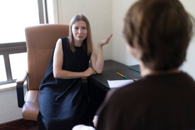 Psikolog, ofisinde terapi seansı sırasında hastasına el hareketleriyle bir şey anlatıyor.