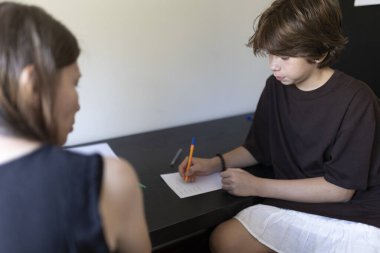 Genç öğrenci, öğretmeniyle birlikte özel bir ders sırasında not alıyor.