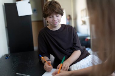 Erkek ve kız evde bir çizim projesinde işbirliği yapıyor, evde eğitimin tadını çıkarıyor ve birlikte yaratıcı aktivitelere katılıyorlar.