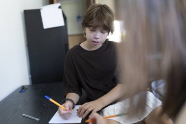 Genç öğrenci sınıf ortamında notlar alıyor, öğrenme ve eğitime odaklanmış.