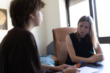 Psikolog, evdeki terapi seansında genç hastasını dinlerken not alıyor.