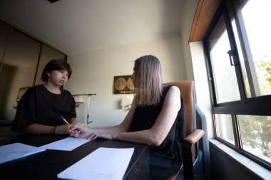 Bir evde terapi seansında genç bir hastaya yardım eden psikolog, destek ve rehberlik sağlıyordu.