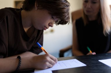 Genç öğrenci özel bir ders sırasında öğretmeninin yardımıyla notlar yazıyor.