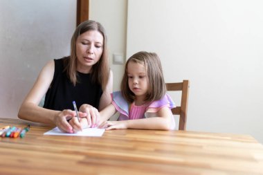 Evde eğitim kavramı, küçük kızına ödevlerinde yardım eden bir anne, ona nasıl yazacağını öğreten bir anne.