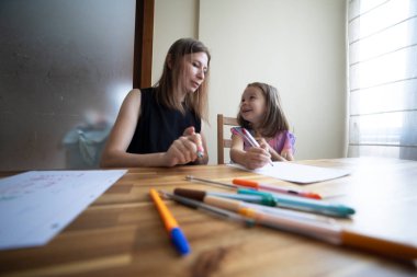 Anne ve kızı, yemek masasında renkli keçeli kalemlerle çizim yaparak yaratıcı zaman geçirmeyi seviyorlar.