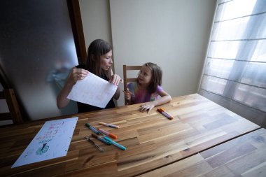 Anne ve kızı evde resim dersinde birlikte resim çiziyorlar.