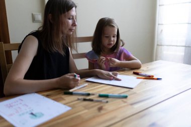 Anne ve kız evde resim çiziyor, evde eğitim görüyor ya da ev ödevi yapıyor.