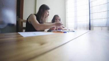 Evde eğitim. Anne, küçük kızına ev ödevinde yardım ediyor, rehberlik ve destek sağlıyor.