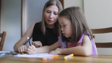 El ve renkli kalemler kullanarak kızına numara öğreten bir kadın.