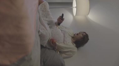 Hamile kadın boş zamanlardan zevk alıyor, televizyon izliyor ve yatak odasında meyve yiyor.