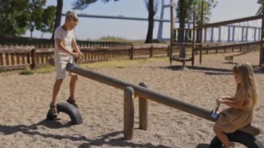 Oyun alanında tahterevallide oynayan mutlu çocuklar.