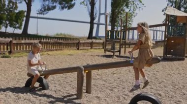 Oyun alanında tahterevallide oynayan mutlu çocuklar.