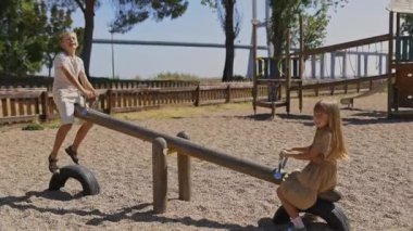 Mutlu çocuklar oyun parkında tahterevalliden zevk alıyorlar.