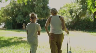 Anne ve kızı parkta yürürken, uzakta oynayan başka bir çocuğu izliyorlar.