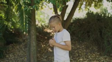 Çocuk parkta oynuyor, ellerine bakıyor ve ekranın dışında biriyle iletişim kuruyor.