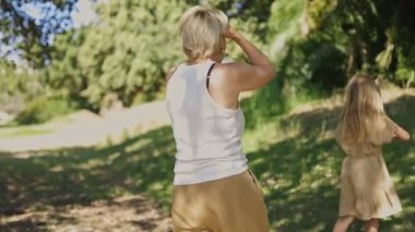 Annesi ve kız kardeşi arka planda oynarken çocuk büyük bir ağaç dalında oturuyor.