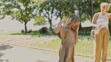 Anne ve kızı güneşli bir yaz gününde parkta yürüyüş yapıyorlar.