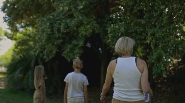 Anne ve çocuklar doğayı keşfediyor ve parktaki ağaçlardan meyve topluyor.